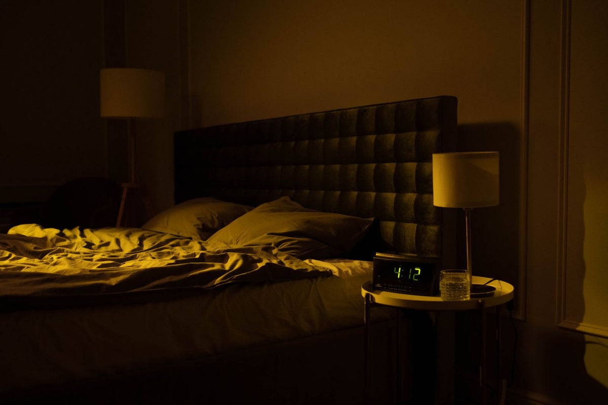Donkere slaapkamer in de nacht met een onopgemaakt bed en een klok