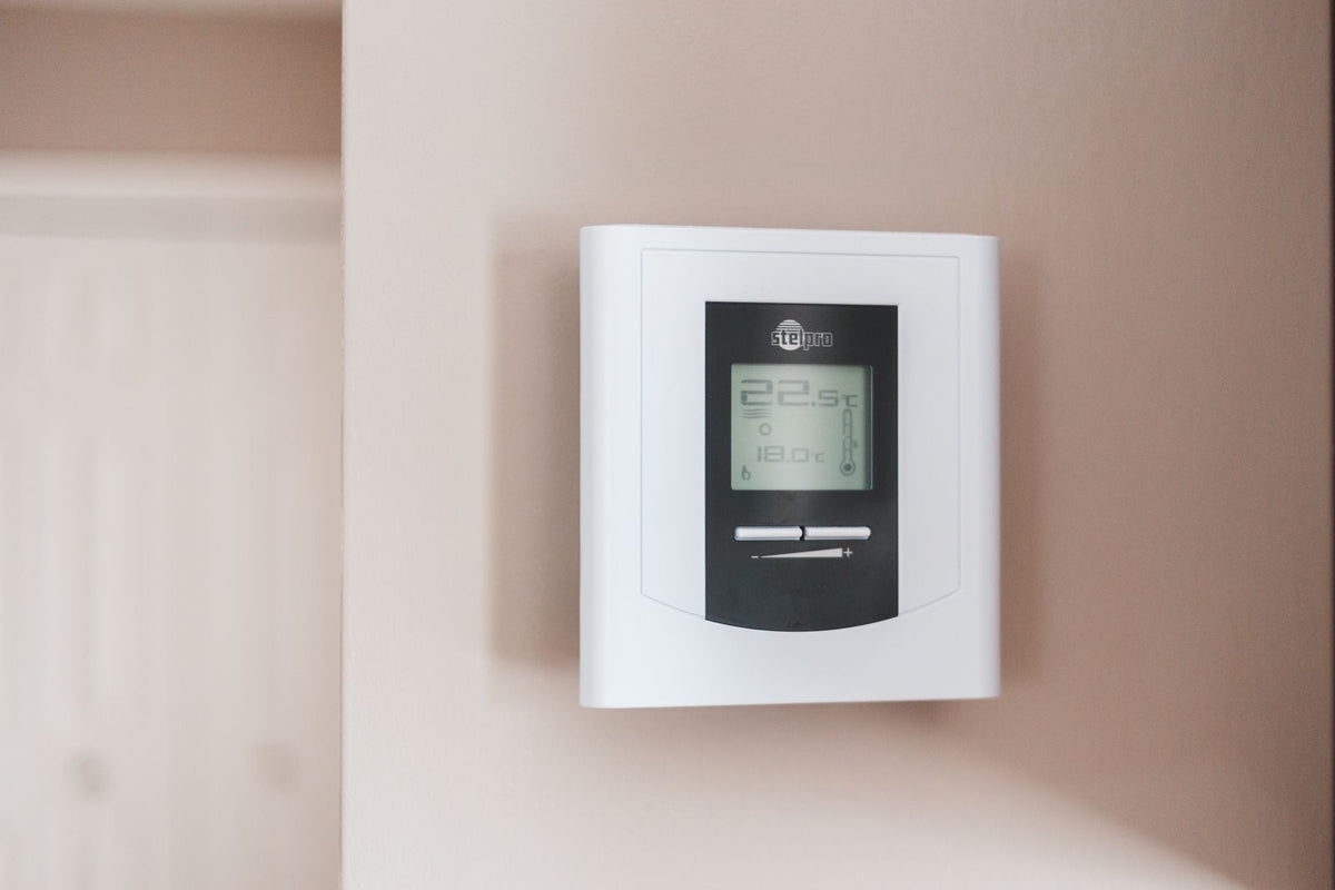 Close-up van een digitale thermostaat aan de muur met temperatuurinstelling