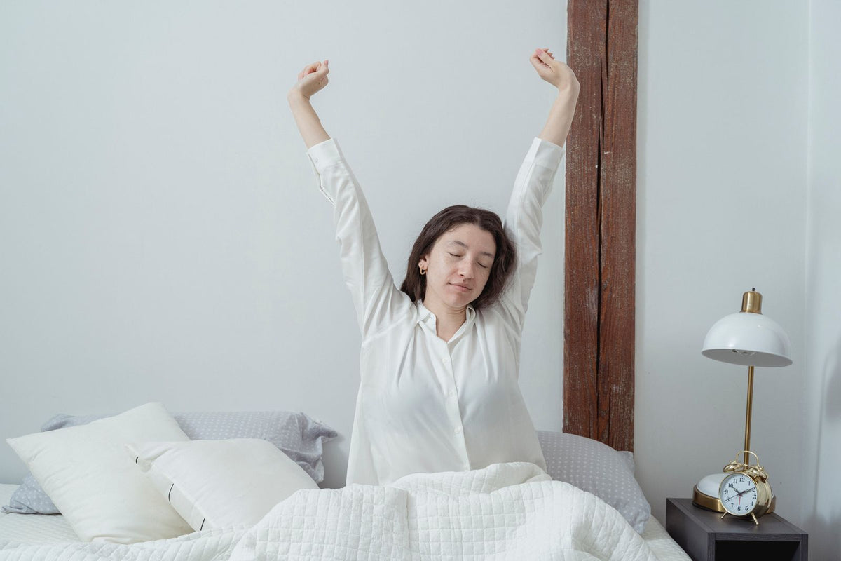 Vrouw die vermoeid wakker wordt in bed in de ochtend