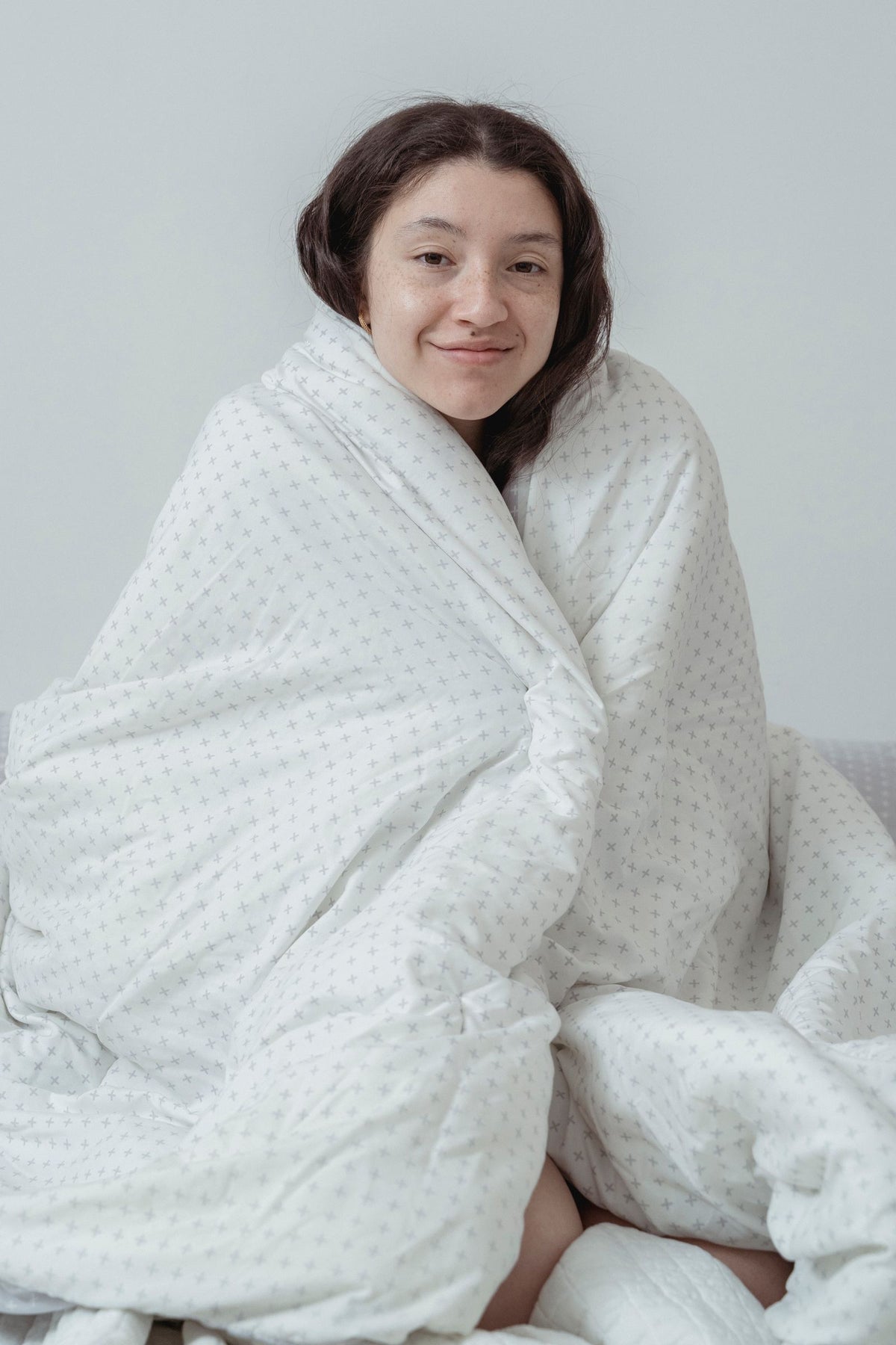 Vrouw gewikkeld in een witte deken, binnen zittend
