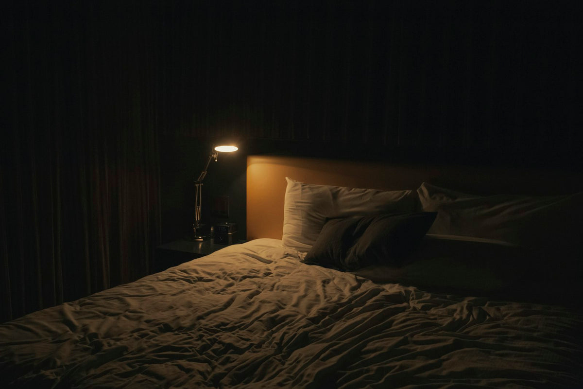 Slaapkamer met bed en nachtlampje, passend bij een luchtontvochtiger die 's nachts aanblijft