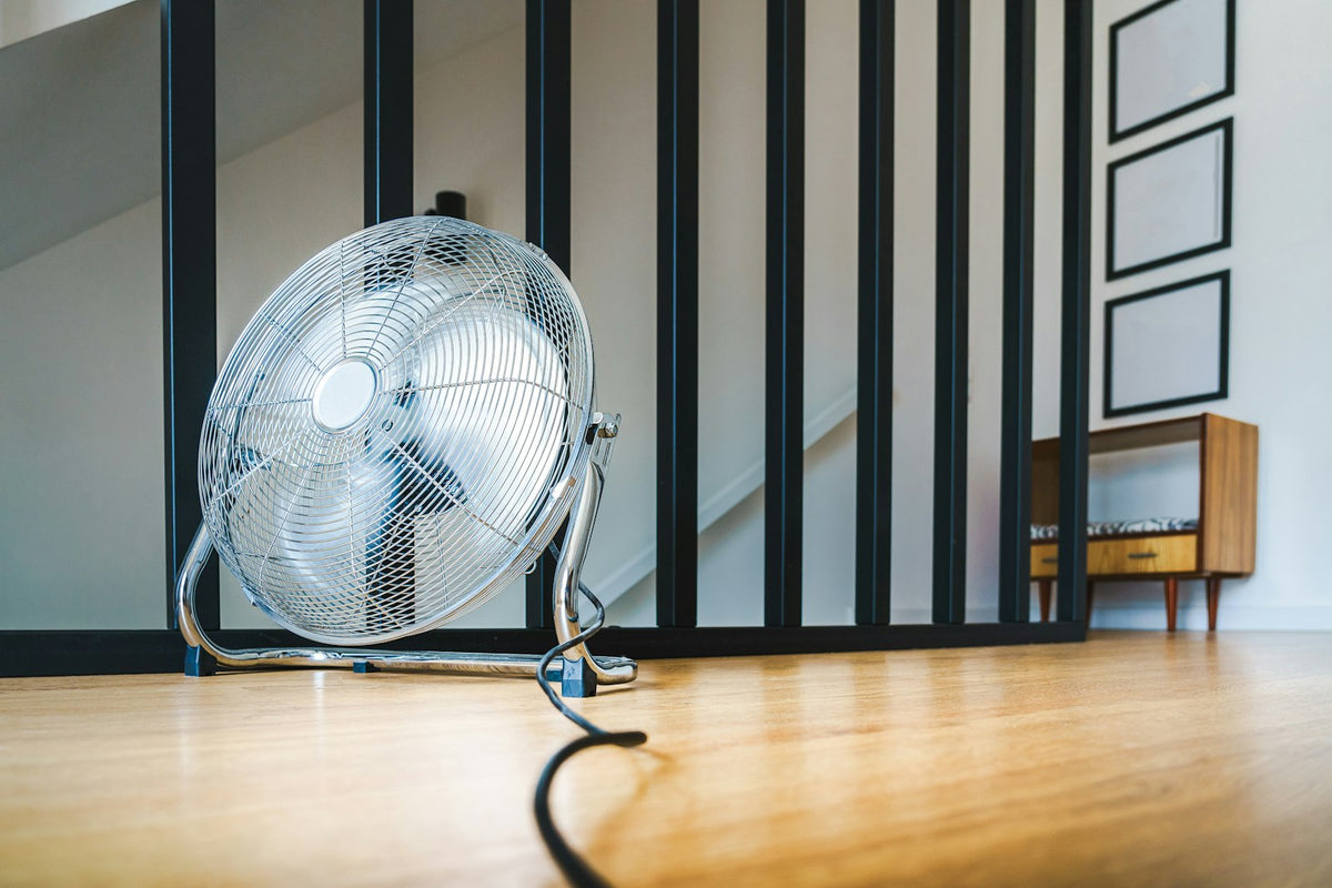 Staande ventilator op de vloer in een woonkamer, passend bij ventilator die 's nachts aanstaat