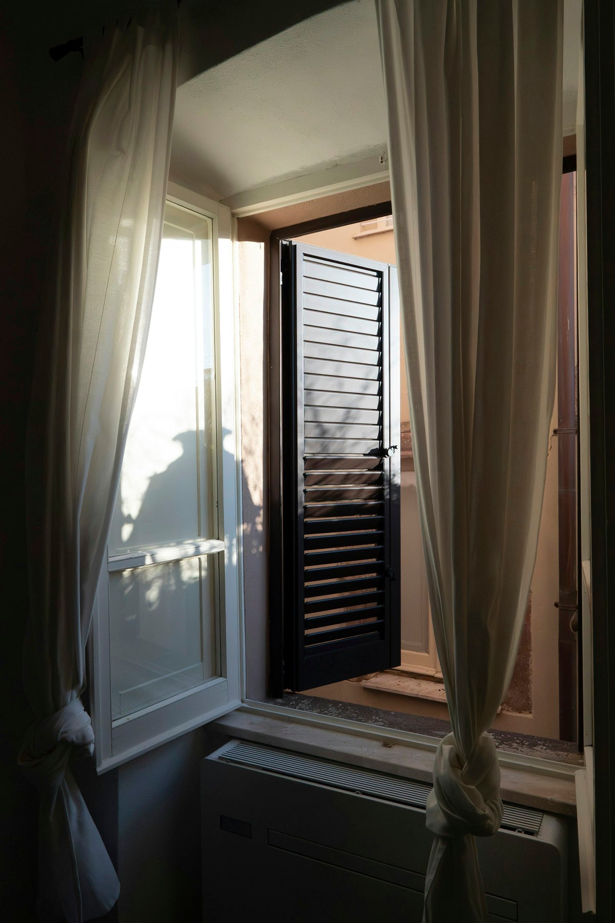 Zonlicht door een open raam met gordijnen, als beeld voor ventilatie en verse lucht in huis
